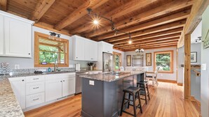 Una cocina amplia con vigas de madera, encimeras de granito y una isla central con taburetes.