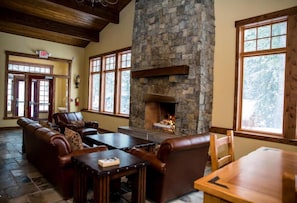 A cozy lounge area with a stone fireplace, leather seating, and large windows.
