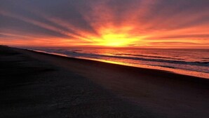 Una puesta de sol sobre una playa con cielo despejado.