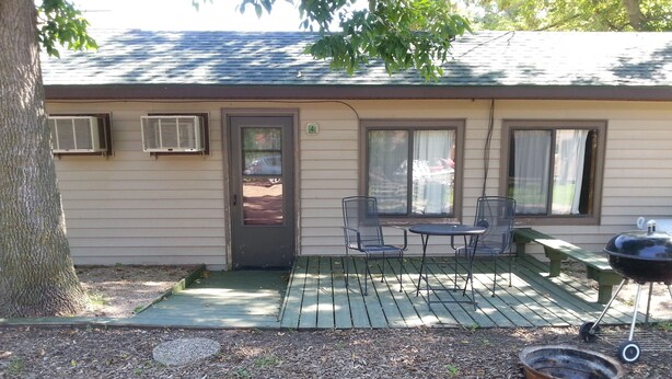 A small house with a patio, a grill, and two chairs. - Cottage 4 is great for family gatherings, & fishing on Lake Osakis! (Osakis)
