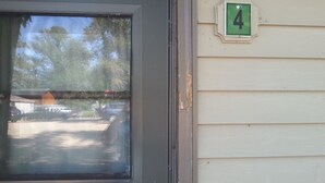 A door with a window, a number '4' sign, and a view of a parking lot with cars and a building in the background. - Cottage 4 is great for family gatherings, & fishing on Lake Osakis! (Osakis)