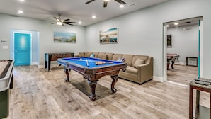 A pool table in a room with a ceiling fan, a sofa, and a door. - HUGE POOL, STOCKED GAME ROOM, SLEEPS 50, 1 min WALK TO BEACH, INCREDIBLE VIEWS!! (North Myrtle Beach)