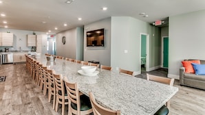 A spacious kitchen with a long dining table, wooden chairs, and a built-in oven. - HUGE POOL, STOCKED GAME ROOM, SLEEPS 50, 1 min WALK TO BEACH, INCREDIBLE VIEWS!! (North Myrtle Beach)