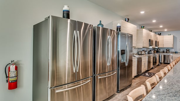 A modern kitchen with stainless steel appliances, wooden cabinets, and a marble countertop. - HUGE POOL, STOCKED GAME ROOM, SLEEPS 50, 1 min WALK TO BEACH, INCREDIBLE VIEWS!! (North Myrtle Beach)