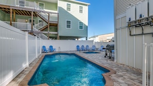A swimming pool with a brick border, surrounded by a white fence and blue chairs. - HUGE POOL, STOCKED GAME ROOM, SLEEPS 50, 1 min WALK TO BEACH, INCREDIBLE VIEWS!! (North Myrtle Beach)