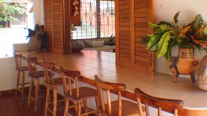 A dining area with wooden chairs and a table, a potted plant, and a decorative item on the wall.