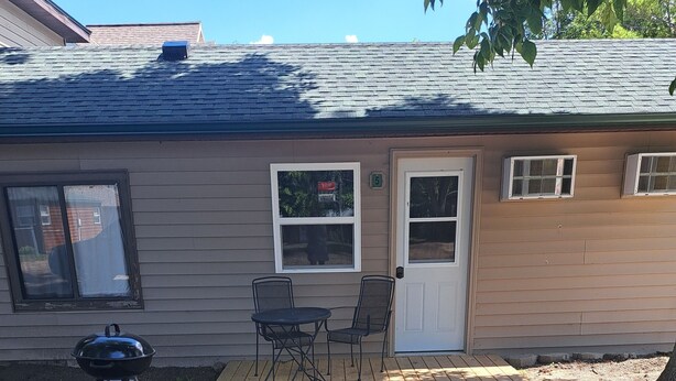A backyard with a barbecue grill, a table and chairs, and a small deck area. - Cottage 5 is great for family gatherings, & fishing on Lake Osakis! (Osakis)