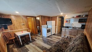 A compact kitchen with a refrigerator, stove, and microwave. There is a dining table with chairs and a sofa. - Cottage 5 is great for family gatherings, & fishing on Lake Osakis! (Osakis)