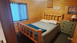 A wooden-paneled room with a bed, a nightstand, a dresser, and a window with curtains. - Cottage 5 is great for family gatherings, & fishing on Lake Osakis! (Osakis)
