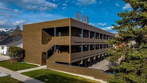 Un bâtiment moderne doté d’une façade en bois, de nombreux balcons et d’un escalier menant aux étages supérieurs.