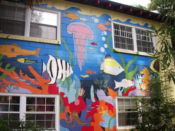 A building with a mural of colorful marine life on its exterior walls.