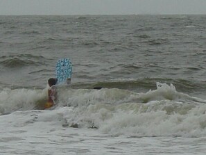 Une personne dans l’eau, tenant une planche de surf bleue à motifs.