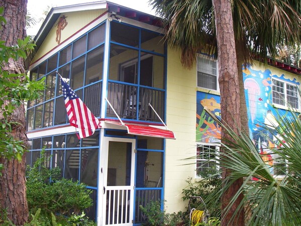 Un bâtiment à deux étages doté d’un balcon, d’un drapeau et d’une fresque murale aux couleurs vives.