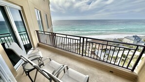 A balcony with two chairs and a view of the ocean and beach. - Beautiful Sunset paradise with New Golf Cart 4811 (Miramar Beach)