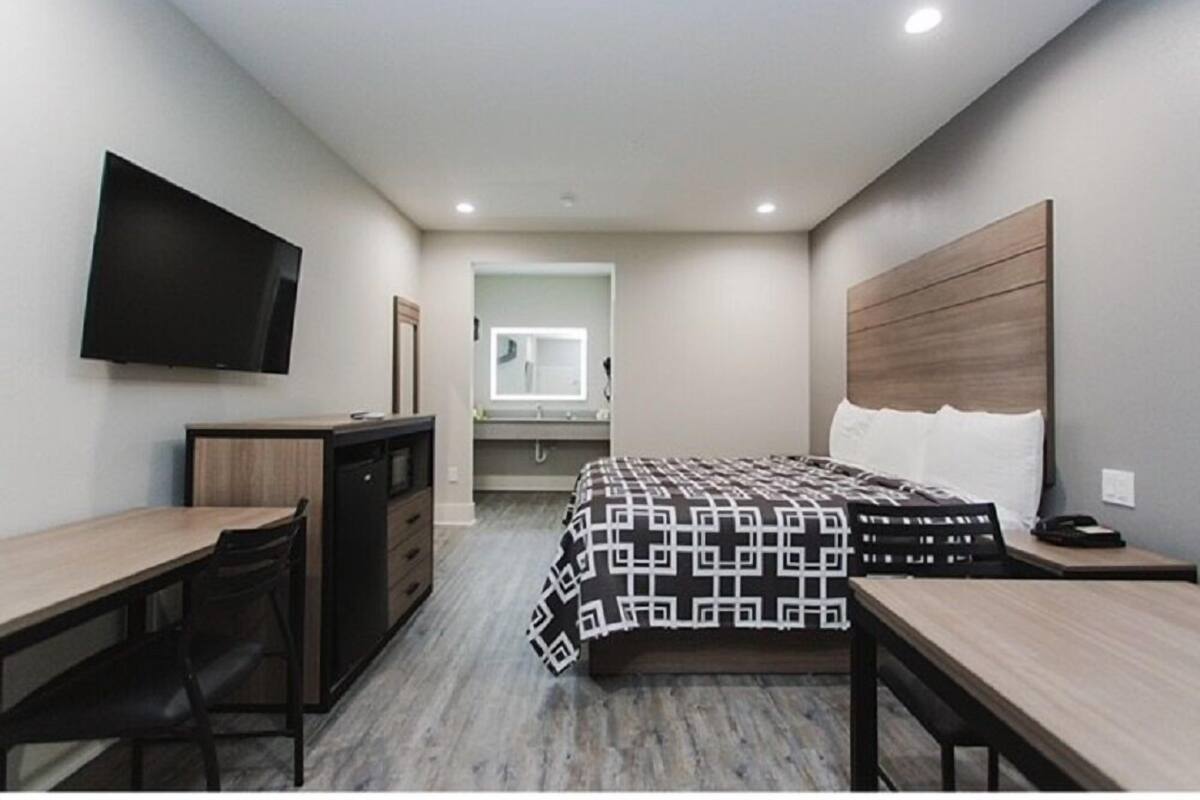 A modern hotel room with a bed, desk, and television.