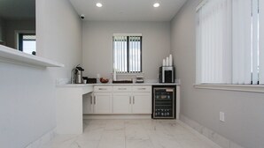 A modern kitchen with white cabinets, a built-in oven, and a refrigerator. - Palace Inn Conroe (Conroe)