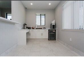 Una cocina moderna con armarios blancos, horno empotrado y refrigerador.