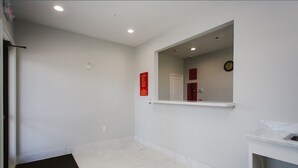 A clean, modern bathroom with white walls, a marble floor, and a large mirror. - Palace Inn Conroe (Conroe)