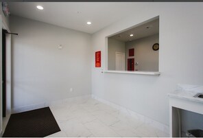 Un baño limpio y moderno con paredes blancas, piso de mármol y un espejo grande.