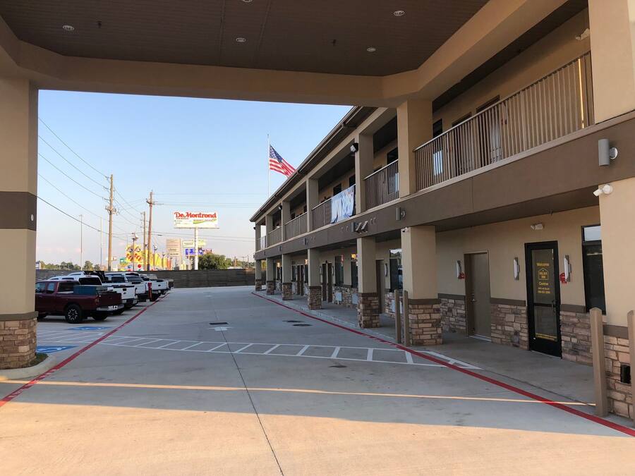 A hotel with a two-story structure, a parking lot, and a visible American flag.