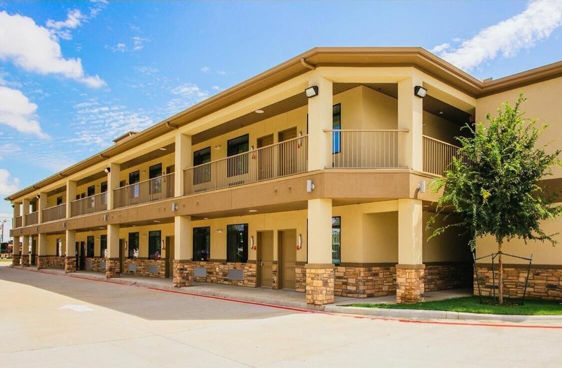 A multi-story hotel with a flat roof, balconies, and a stone facade.