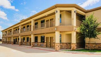 A multi-story hotel with a flat roof, balconies, and a stone facade.