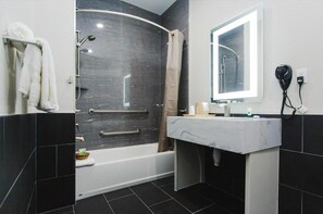 A modern bathroom with a bathtub, a shower, and a vanity with a mirror.