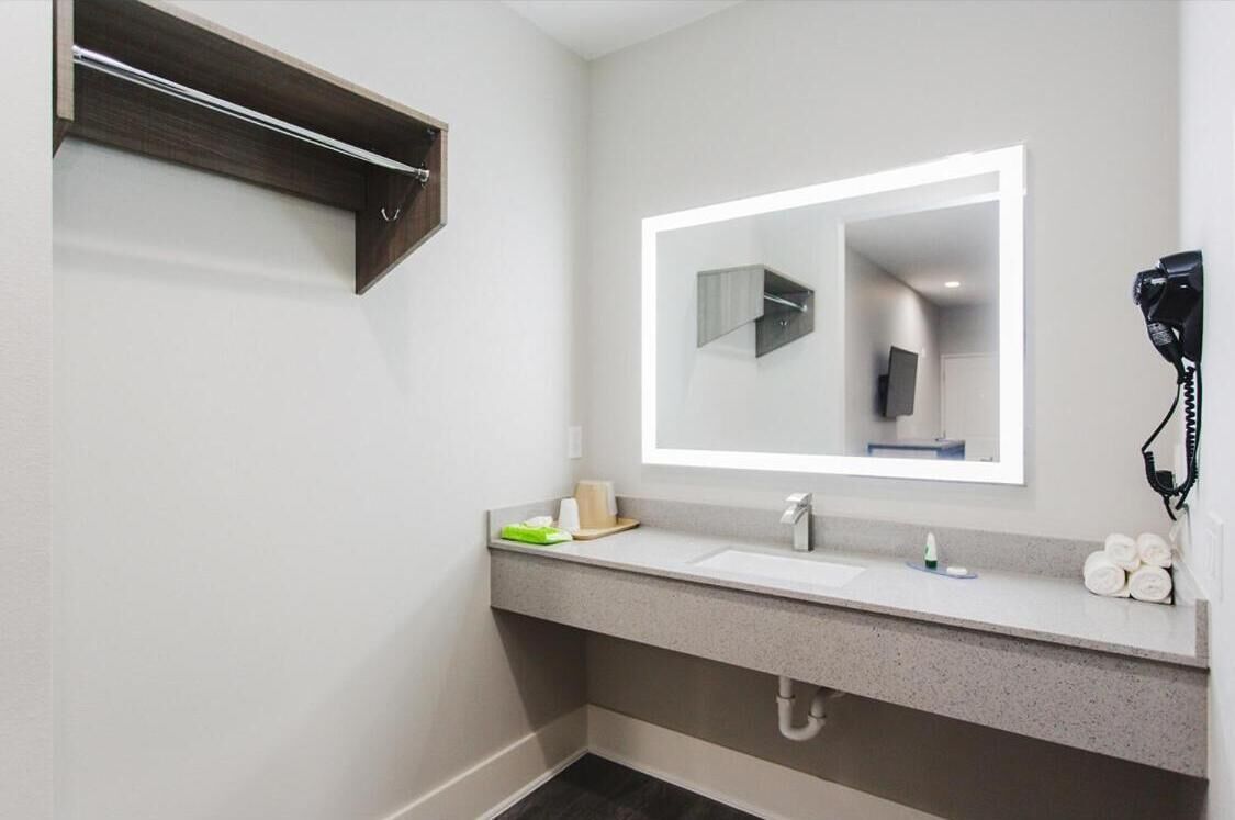 A modern bathroom with a large mirror, a hairdryer, and a towel rack.