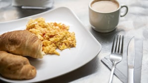 A breakfast plate with scrambled eggs and croissants, a cup of coffee, and cutlery on a marble table. - Ayenda 1016 Bogotá Chapinero (Bogotá)