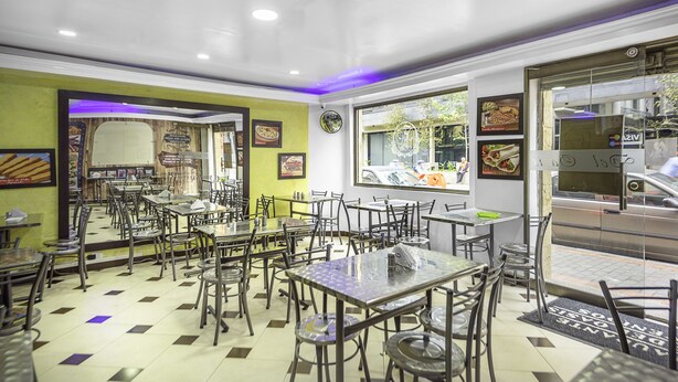 A restaurant with multiple tables and chairs, a tiled floor, and a view of the street outside. - Ayenda 1016 Bogotá Chapinero (Bogotá)