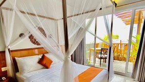Une chambre d’hôtel avec un lit sous un dais, une tête de lit en bois et une vue sur l’espace extérieur grâce à de grandes portes-fenêtres coulissantes.