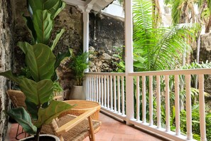 A balcony with wicker furniture, potted plants, and a white railing.
