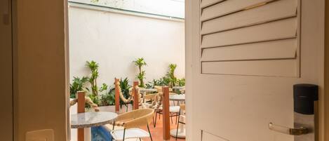 An open door to a courtyard with outdoor seating, a pool, and potted plants.