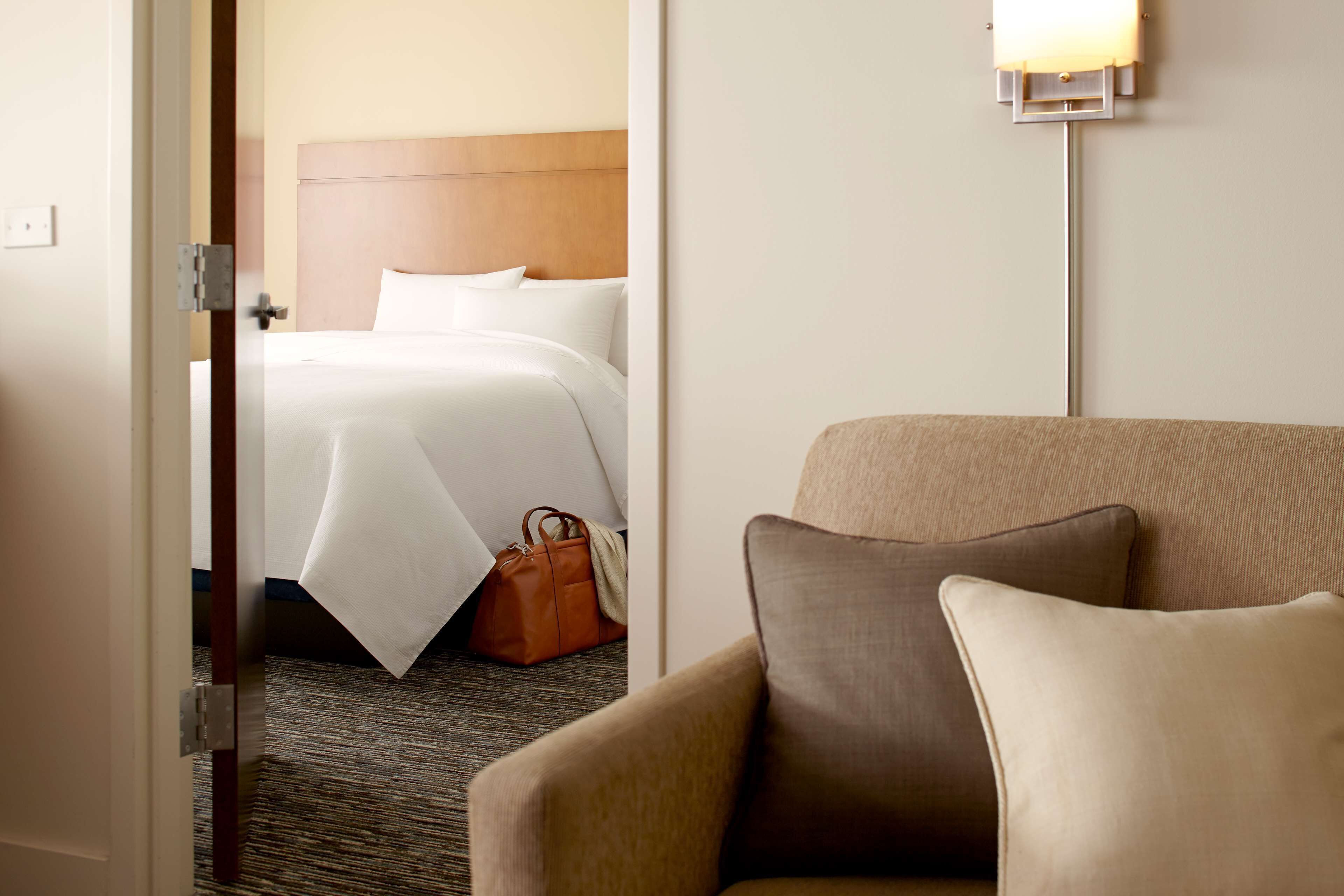 A hotel room with a bed, a chair, and a lamp.