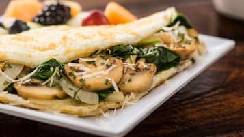A plate of food with a folded omelette, vegetables, and cheese.