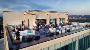 A rooftop bar with outdoor seating, a bar area, and a view of a cityscape. - Hyatt House Augusta Downtown (Augusta)