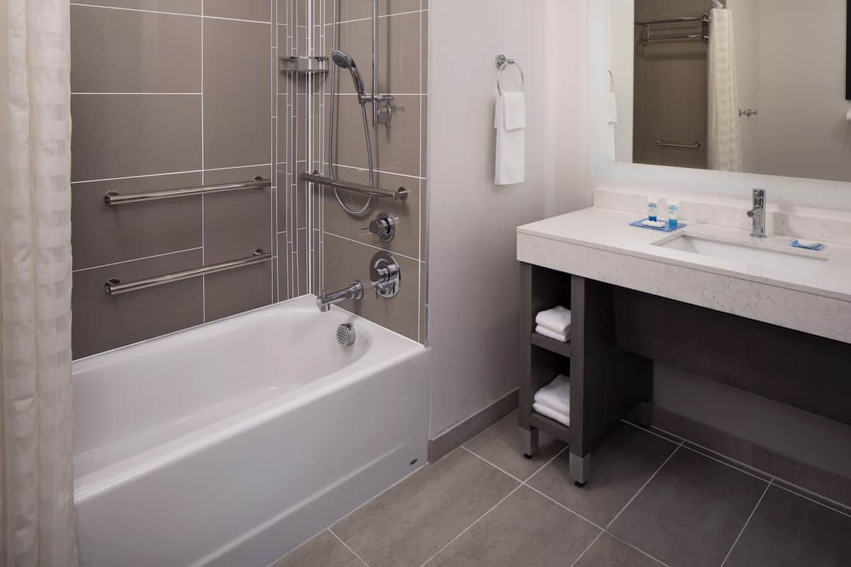 A modern bathroom with a bathtub, shower, and vanity.