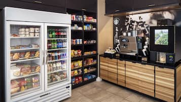 A self-service kiosk with a coffee machine and a screen displaying a coffee shop scene.