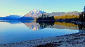 Un lago tranquilo con una montaña al fondo y una orilla cubierta de bosque.