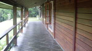 A covered porch with wooden walls and a stone floor.