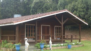 A wooden cabin with a porch, large windows, and a covered area.