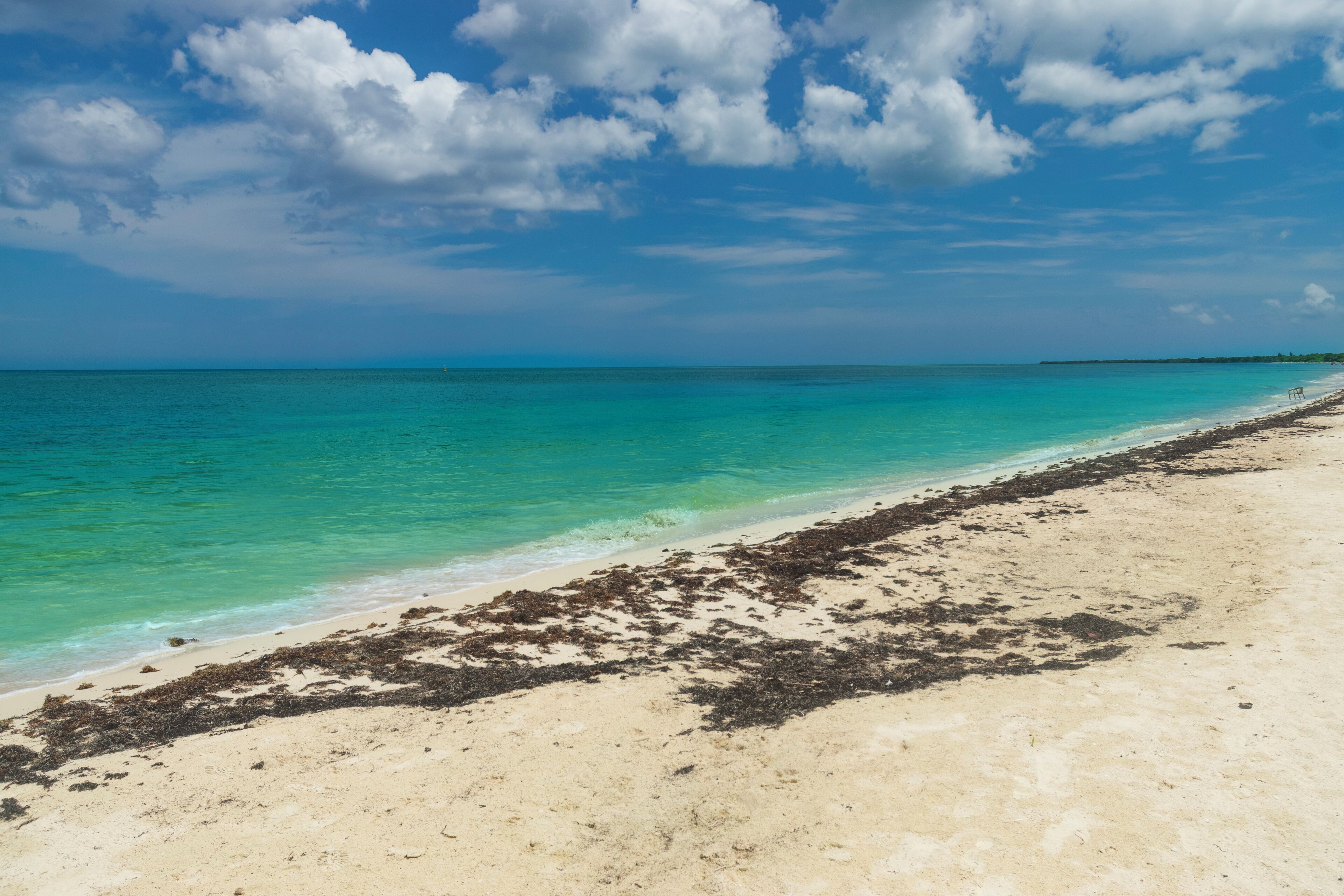A beach with clear turquoise water and a sandy shore.