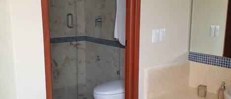 Un baño con ducha, inodoro y tocador.
