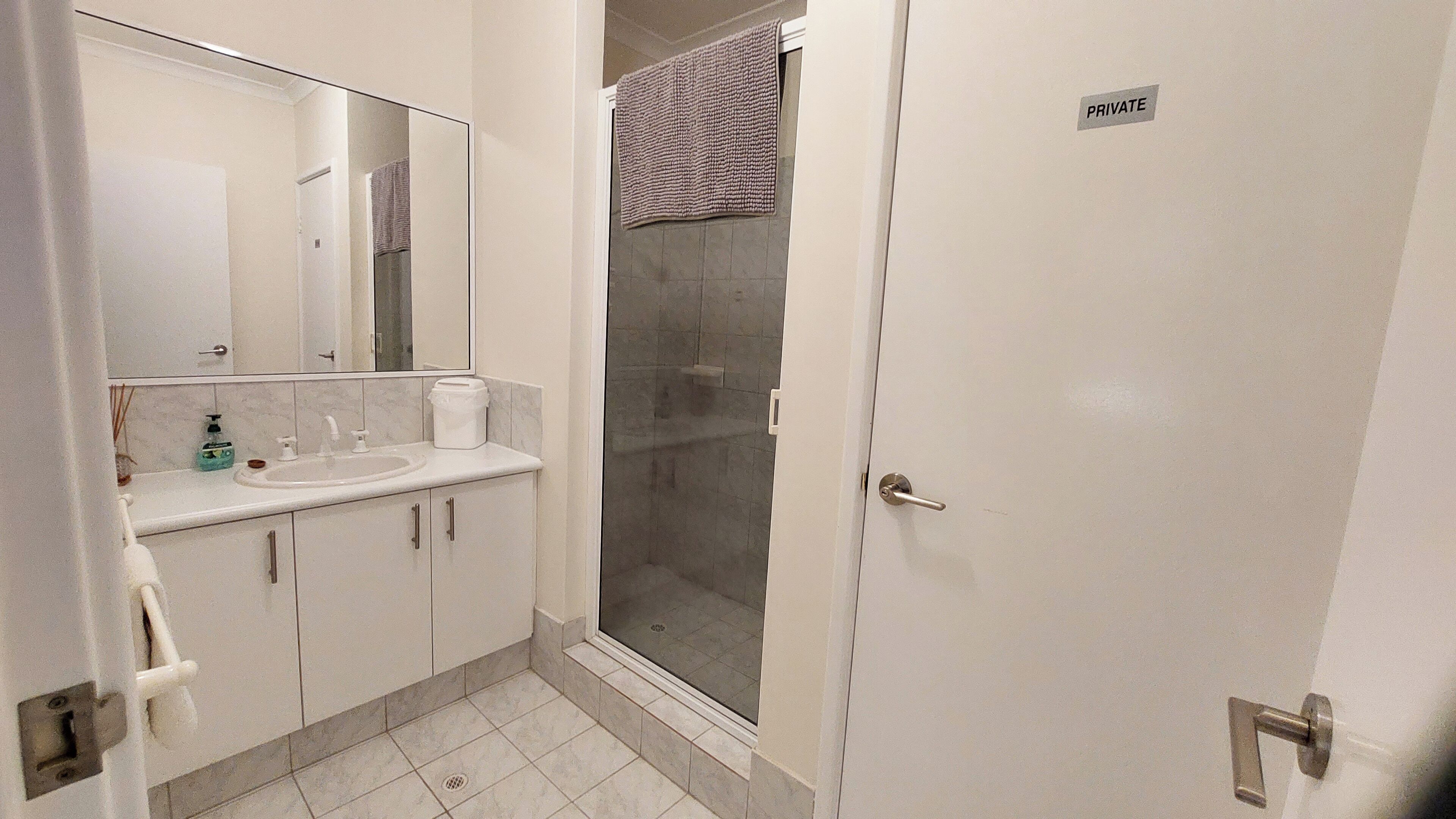 A bathroom with a sink, mirror, and shower.