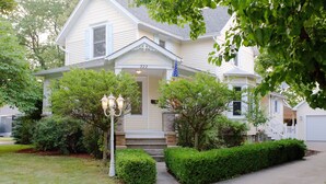 Une maison à deux étages avec un porche à l’avant, une boîte aux lettres et un lampadaire.
