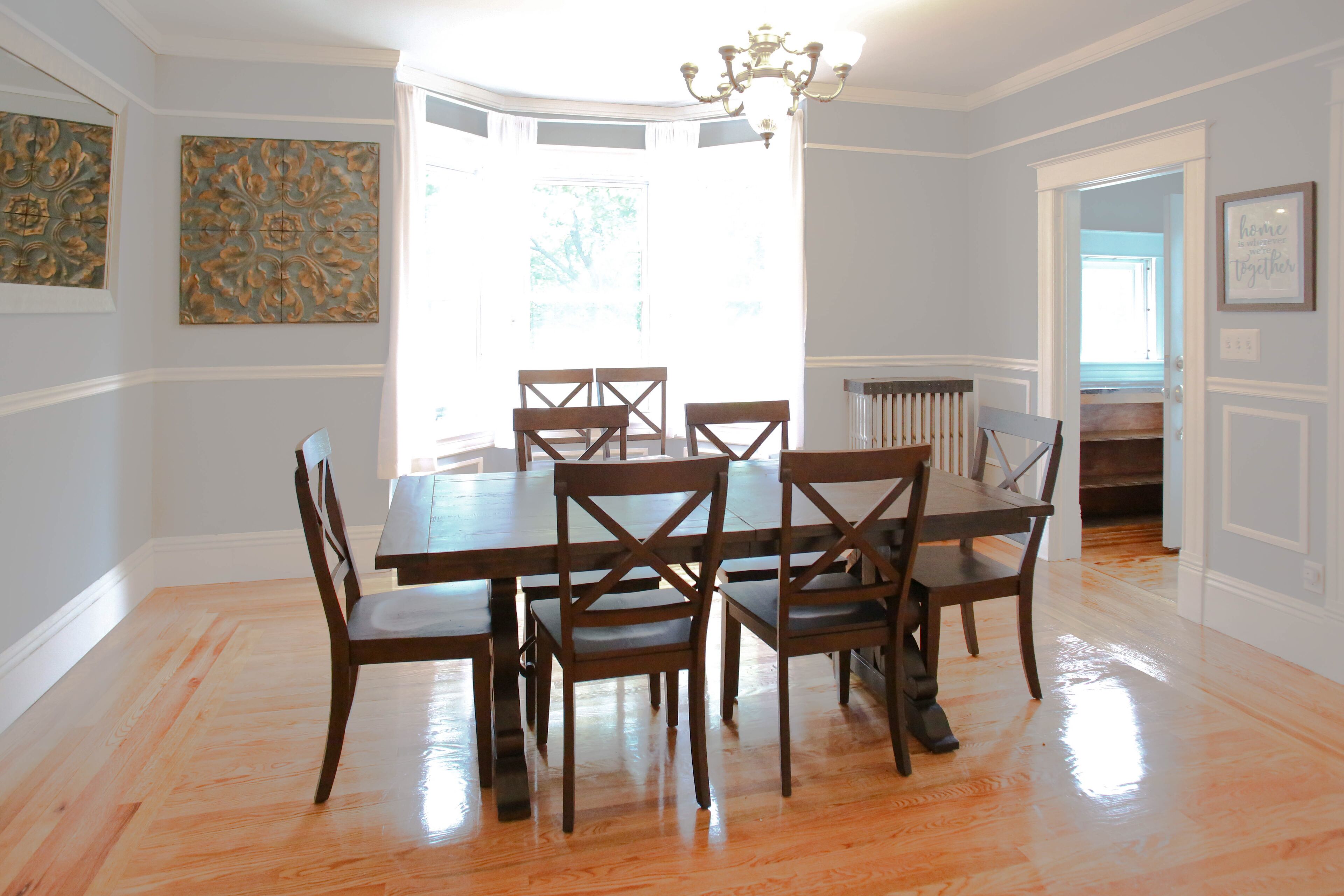 A dining room with a wooden table and chairs, a chandelier, and decorative wall art.