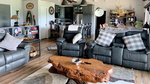 Ein geräumiges Wohnzimmer mit Ledersofas, einem Holztisch und einem Deckenventilator.
