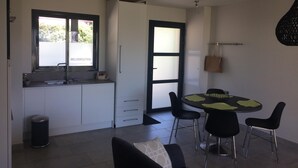 Eine moderne Küche mit weißen Schränken, einem Fenster und einer Essecke mit rundem Tisch und Stühlen.
