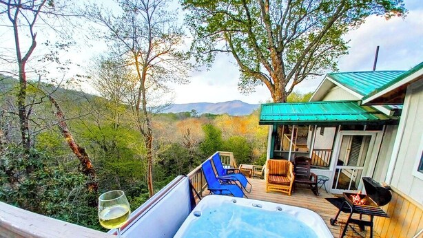 A hot tub on a deck with a view of trees and mountains, a covered patio area, and a grill. - Amazing View! Sauna Gameroom Firepit Spa Room Rustic Spacious Private Retreat  (Banner Elk)