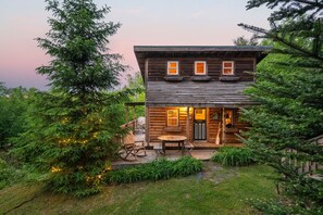 A wooden cabin with a porch, a table, and chairs.